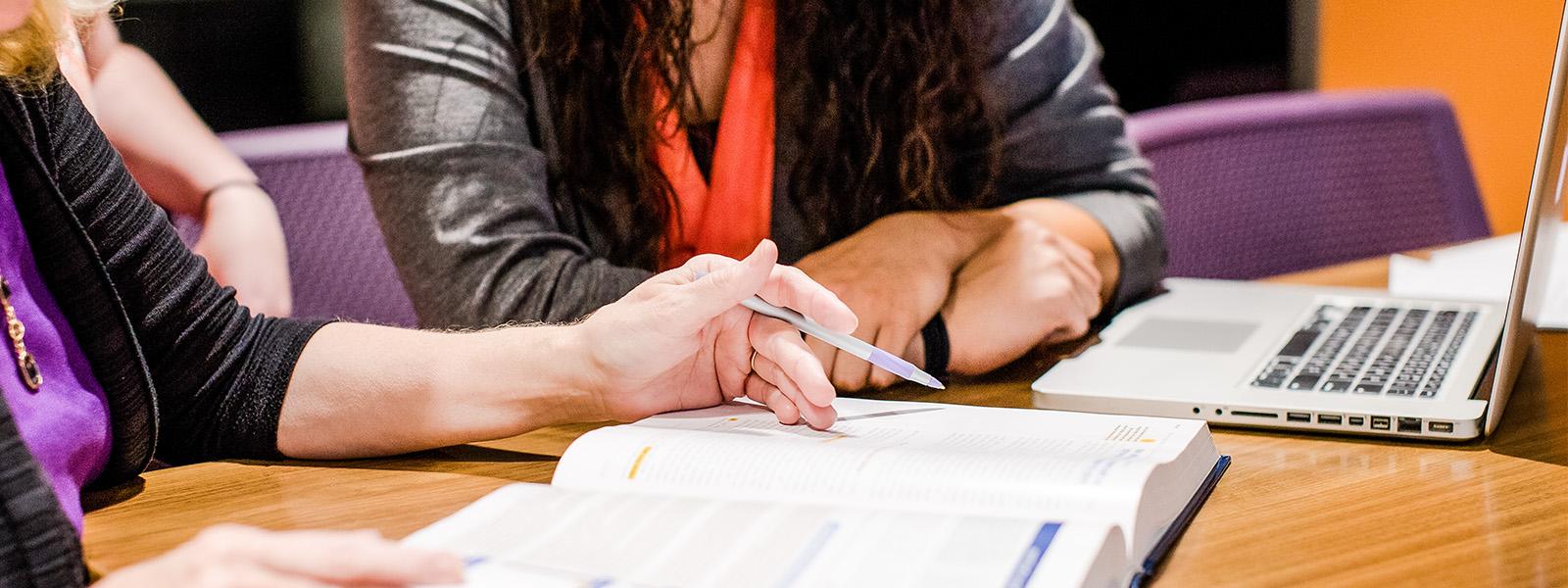 accounting professor looks at computer with student to help her with homework assignment